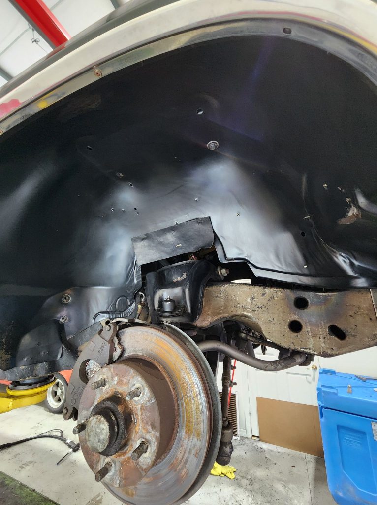 Close-up of car wheel well with visible brake disc.