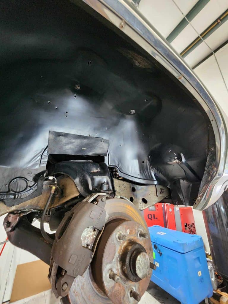 Auto wheel well with brake components exposed.