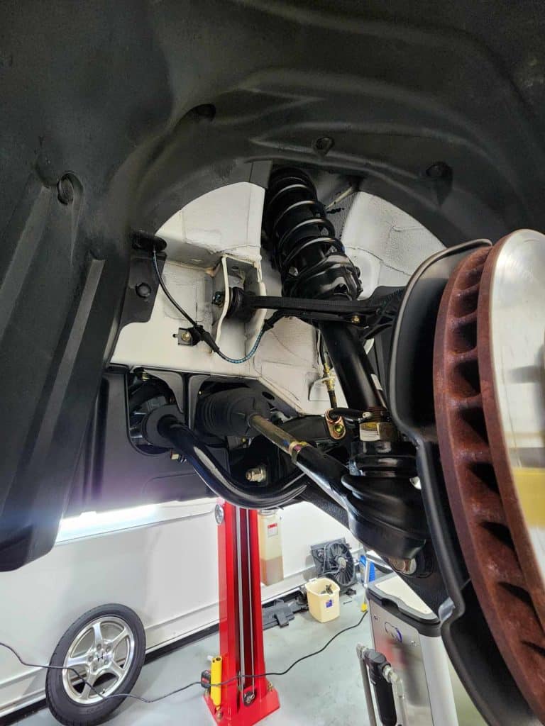 Car suspension system on hydraulic lift in workshop.
