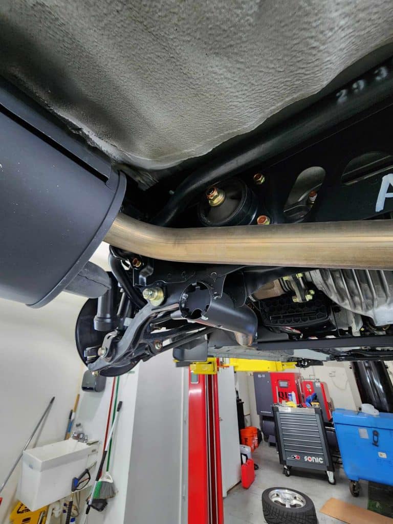 Car undercarriage showing exhaust system and suspension parts.